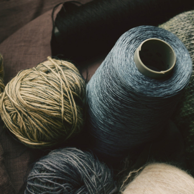 A close up of balls and spools of yarn in subdued blue and gray colours.